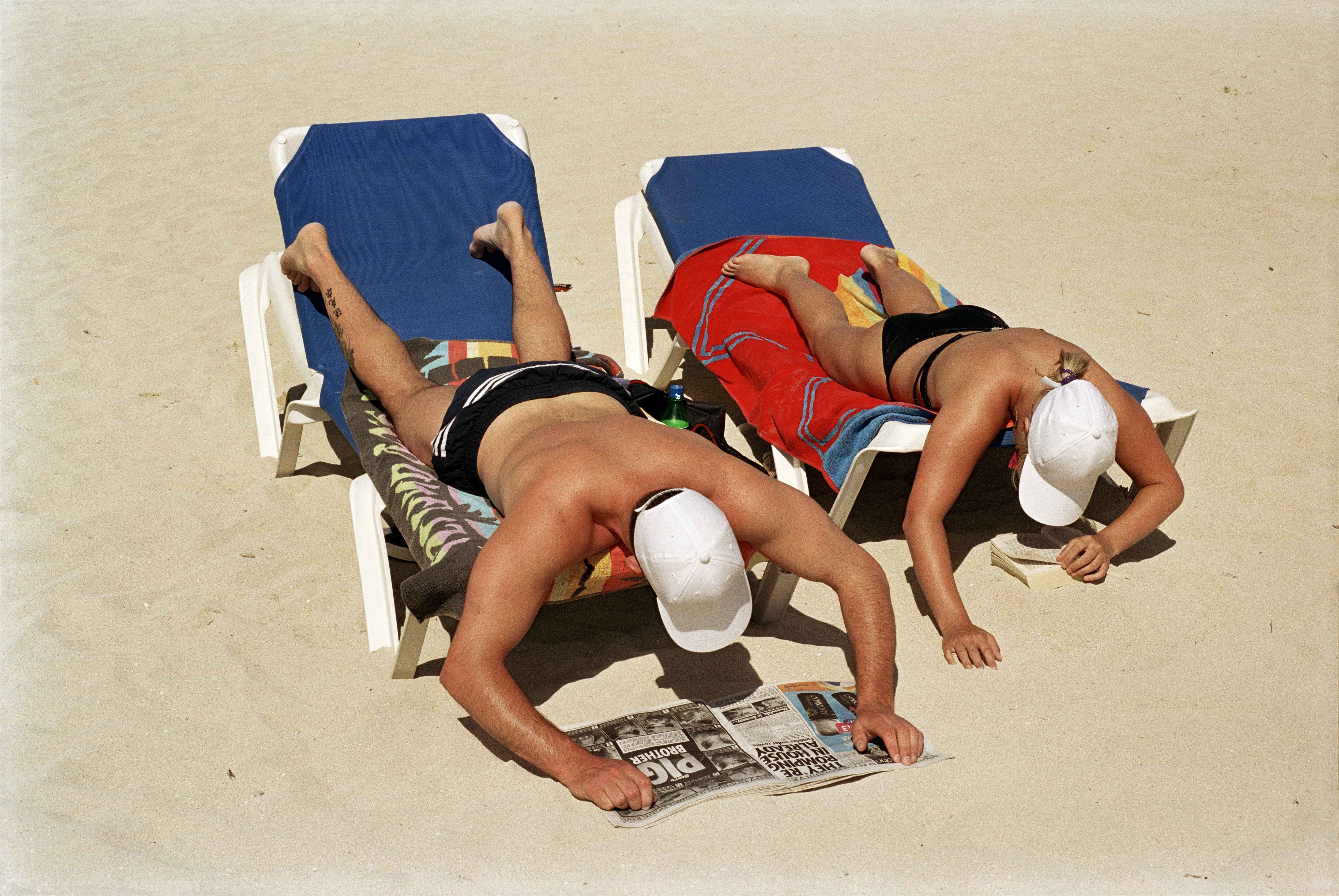 SPAIN. Majorca. Magaluf. Sunbathing and reading on the beach. 2003.